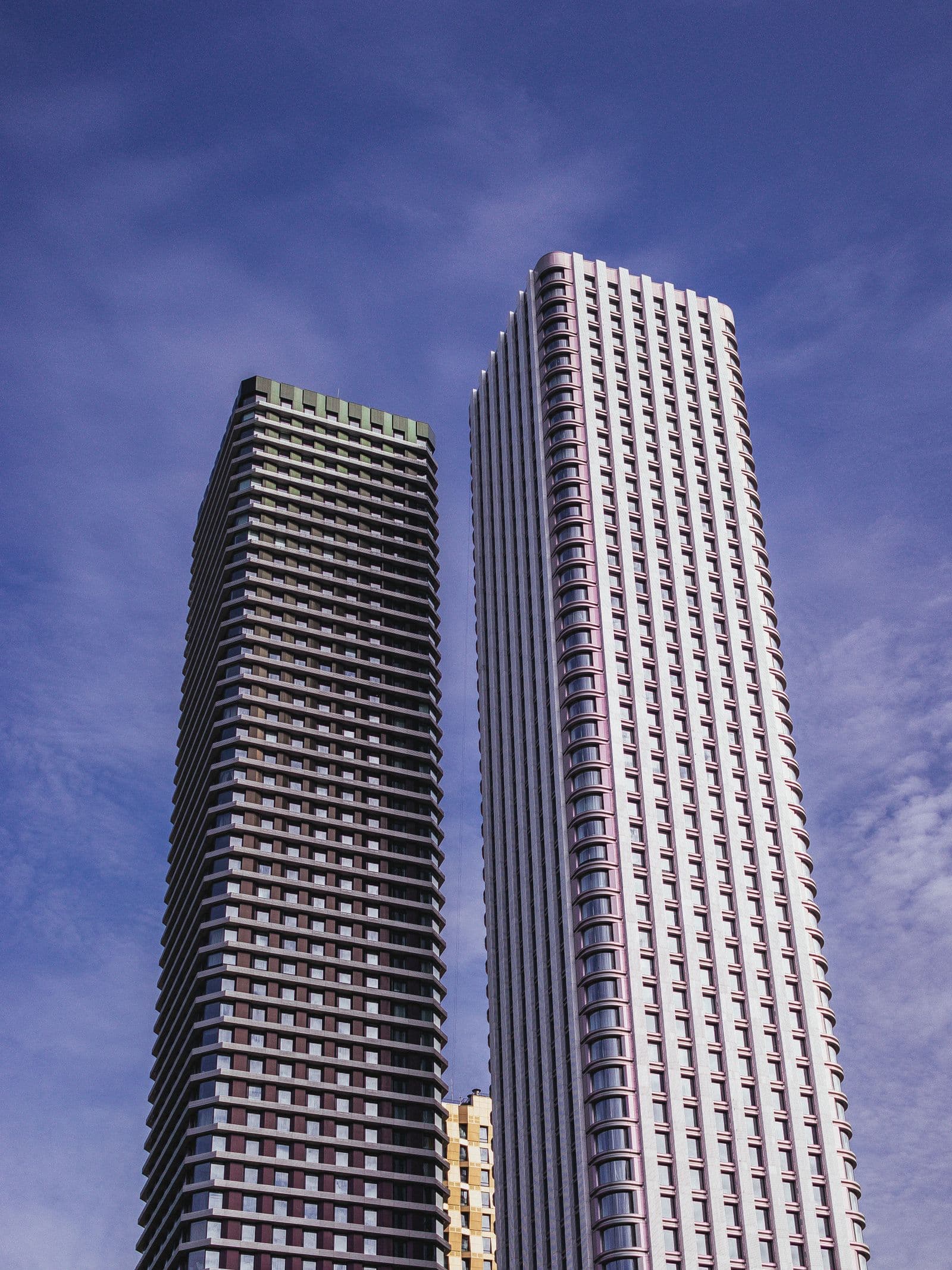 Two office towers side by side against a blue sky