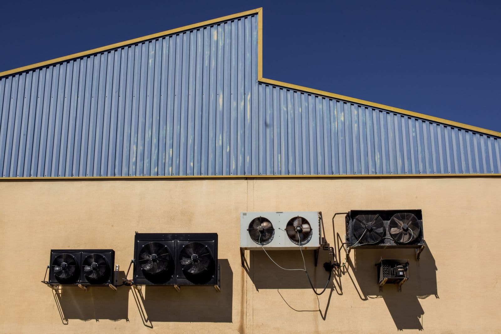 Rooftop condenser units mounted along a low commercial building