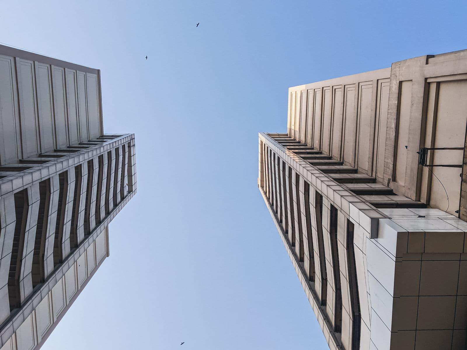 Two concrete towers seen from the street, looking up at open sky